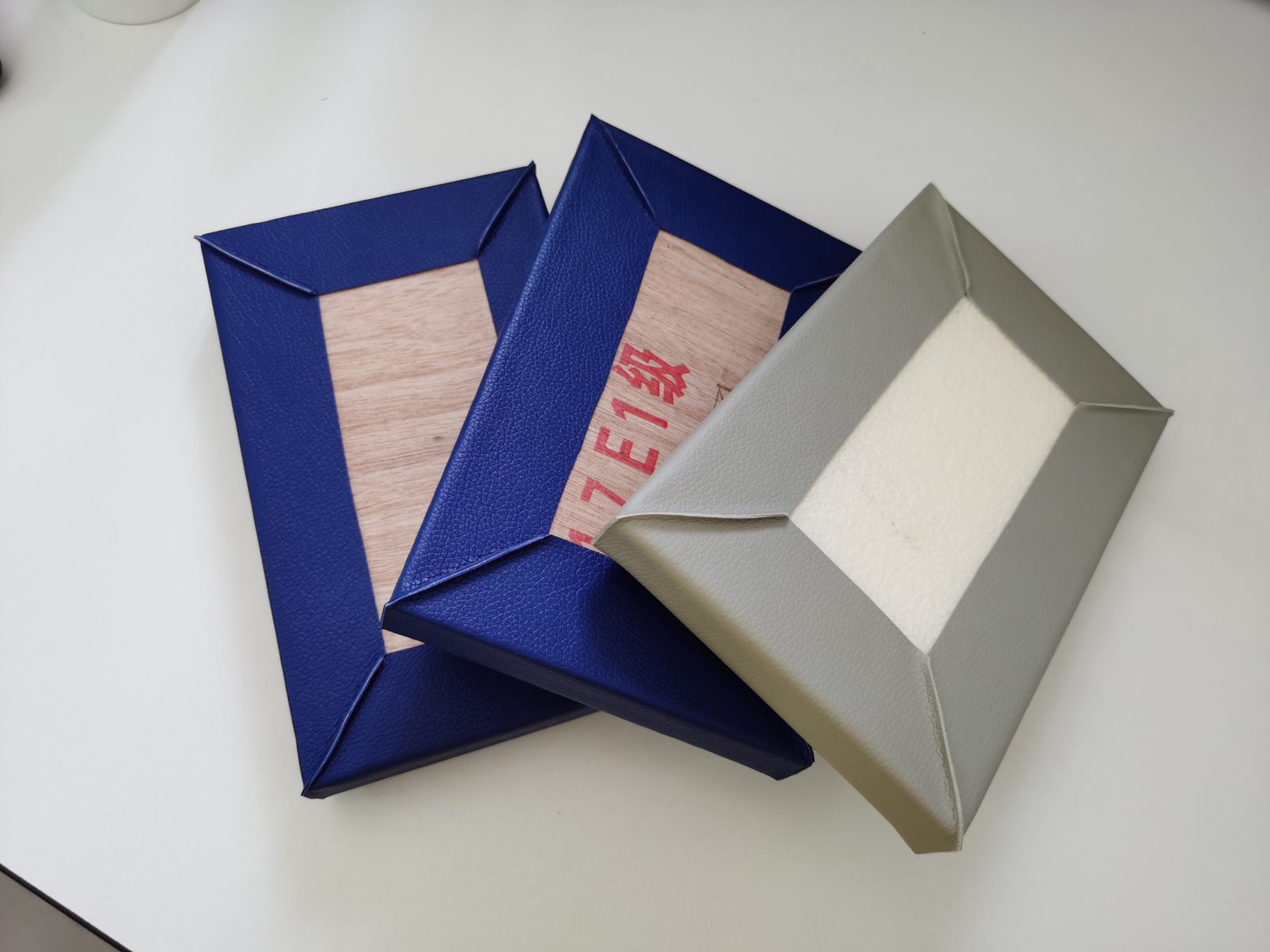 皮革包覆防撞软包墙板样品，背面展示E1级木板底板与高密度海绵结构，适用于办案区审讯室防撞装修