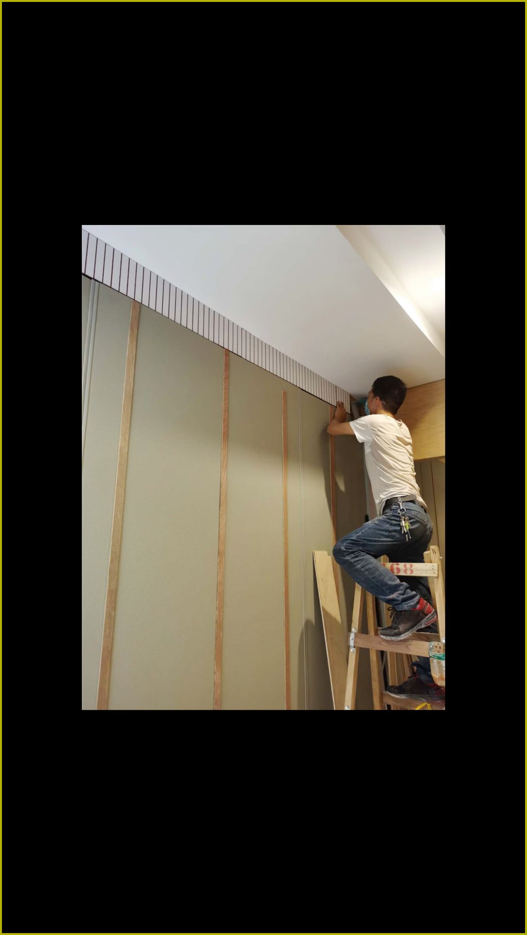 工人站在木梯上安装槽木吸音板，墙面竖向木条声学装饰板条施工实景