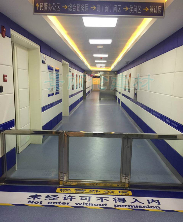 公安办案区走廊白色防撞软包墙面装修实景，蓝色饰条软包墙板防自伤设计，涵盖讯问区候问区