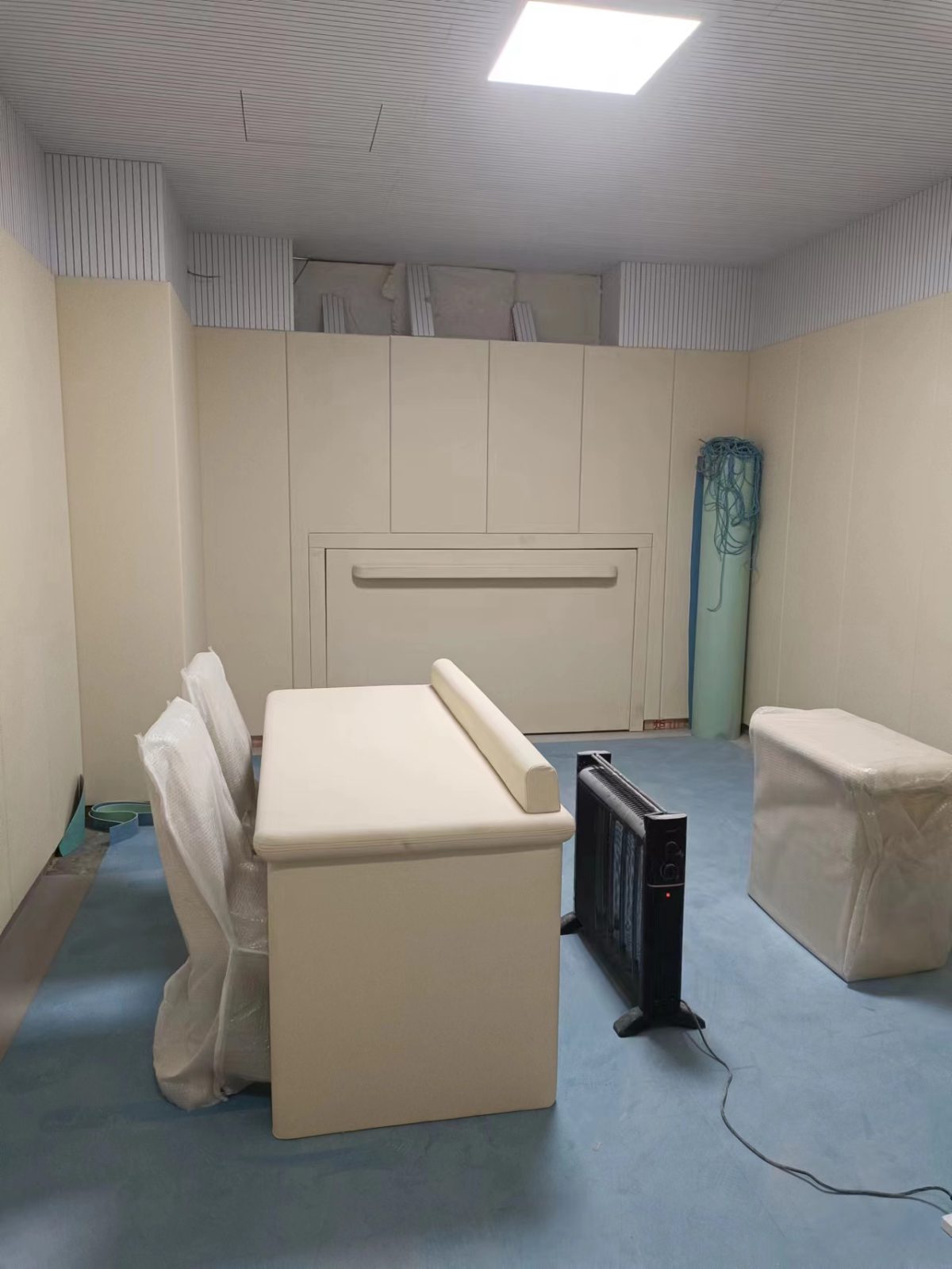 办案区询问室米色防撞软包墙面与防撞桌椅整体装修实景，高密度海绵软包防自伤设计