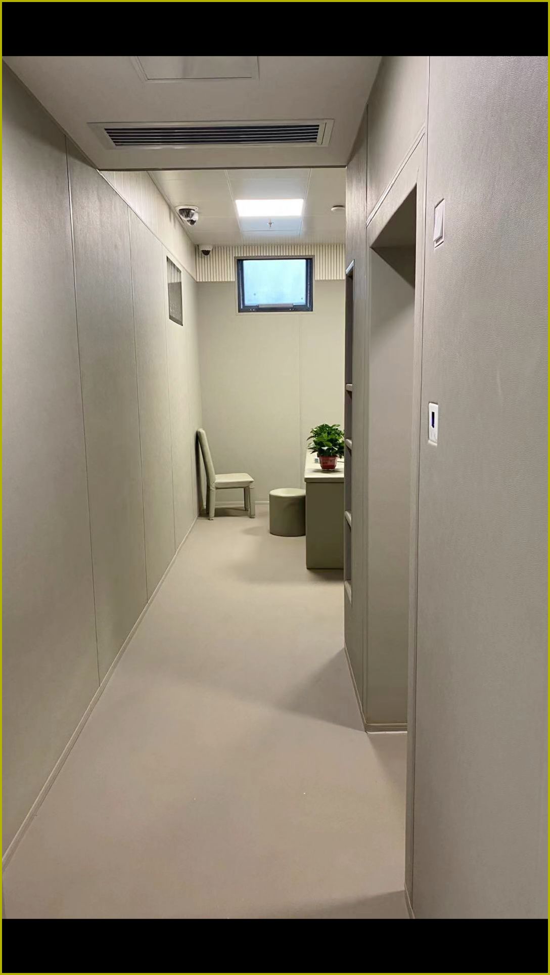 办案区谈话室米色皮革防撞软包墙面整体装修实景，搭配软包桌椅与圆角防撞家具