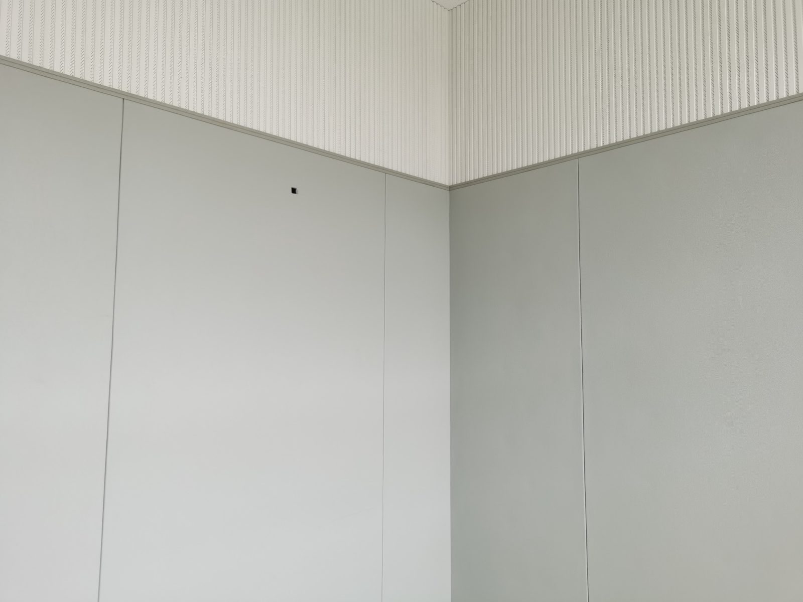 办案区审讯室灰色防撞软包墙面安装实景，无缝软包板搭配上部穿孔吸音板防自伤设计